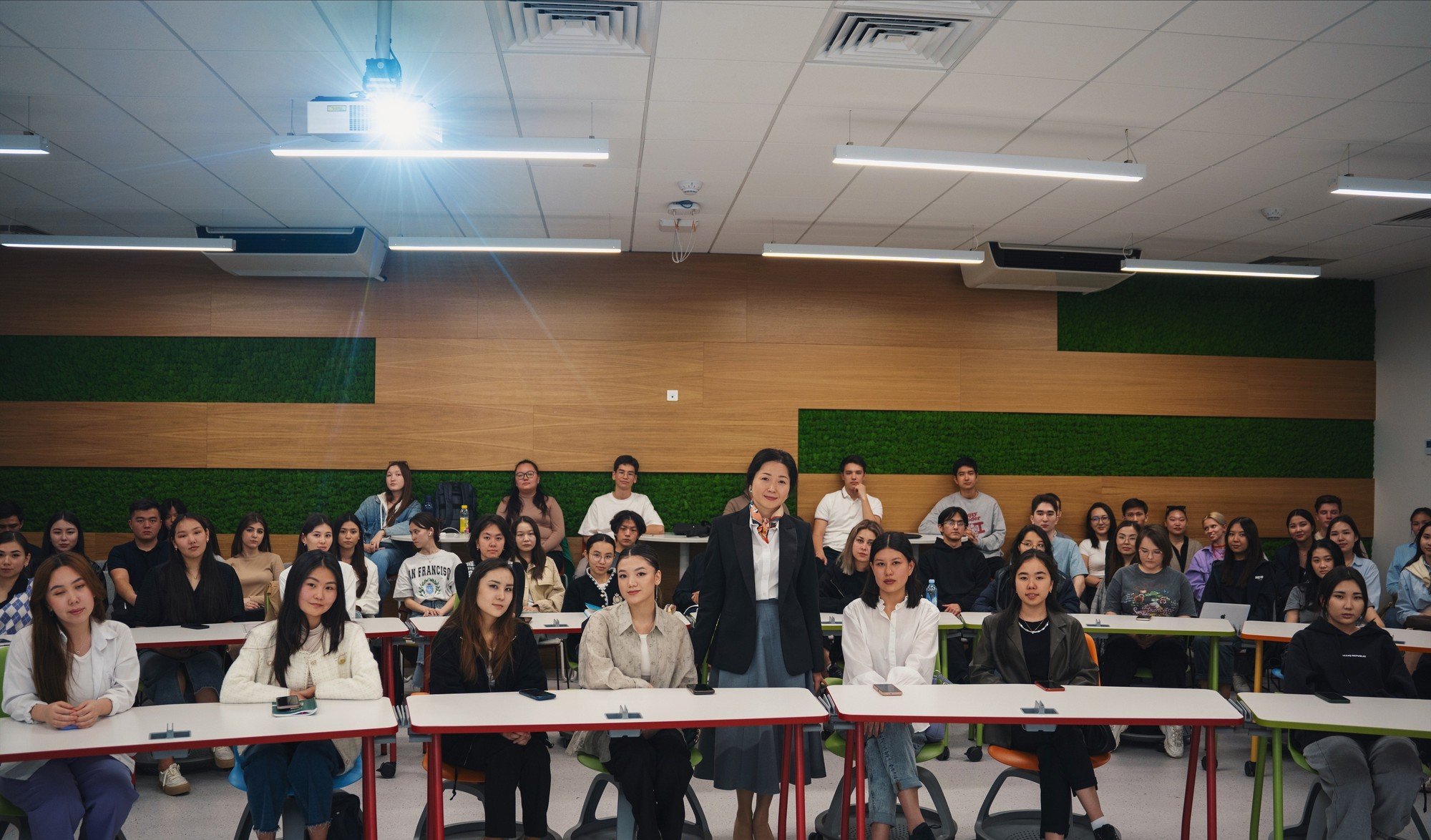 A speaker presenting to engaged students in a modern lecture hall